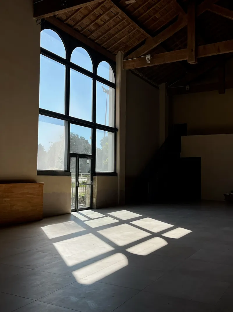Baie vitrée cintrée projetant la lumière du jour sur le sol d'une salle vide