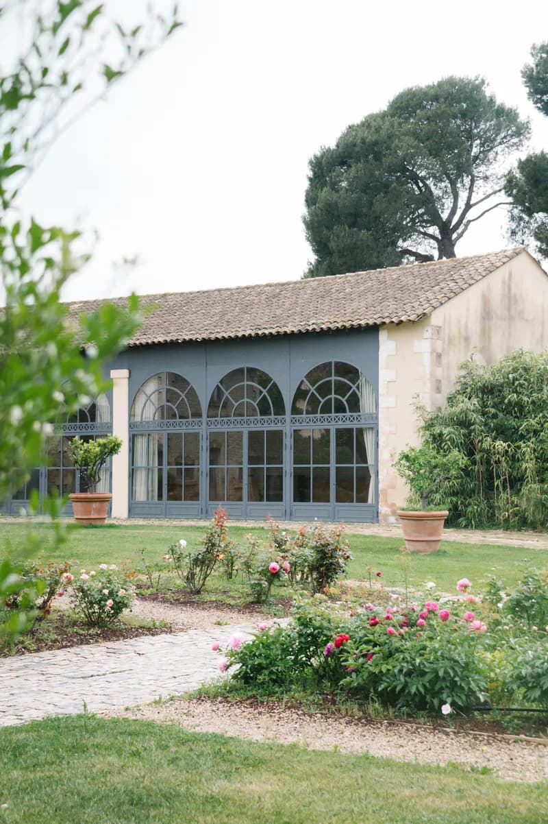 Verrières cintrées d'un bâtiment de réception, devant une roseraie en fleurs