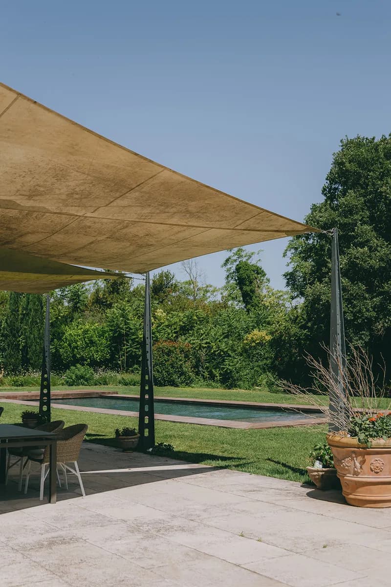 Terrasse ombragée par une voile tendue, avec salon de jardin face à la piscine