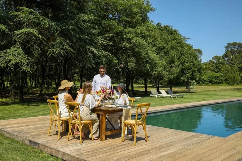 Repas dressé sur la terrasse en bois au bord de la piscine, sous les arbres