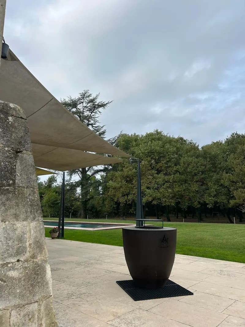 Brasero sur une terrasse en pierre, sous la voile d'ombrage face à la piscine
