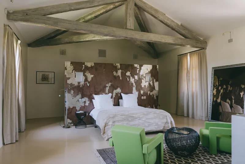 Chambre sous charpente apparente, avec lit double et fauteuils verts