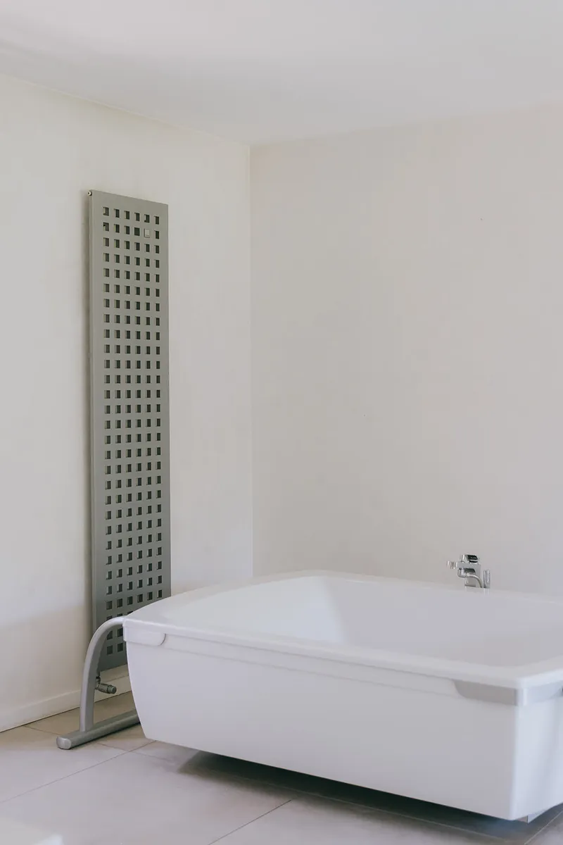 Baignoire îlot dans une salle de bains blanche avec sèche-serviettes