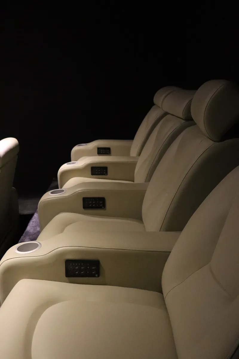 Fauteuils inclinables d'une salle de cinéma, avec accoudoirs et porte-verres
