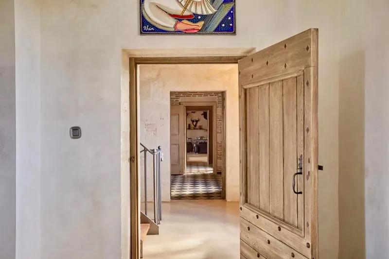 Porte en bois ouverte sur une enfilade de pièces aux sols clairs