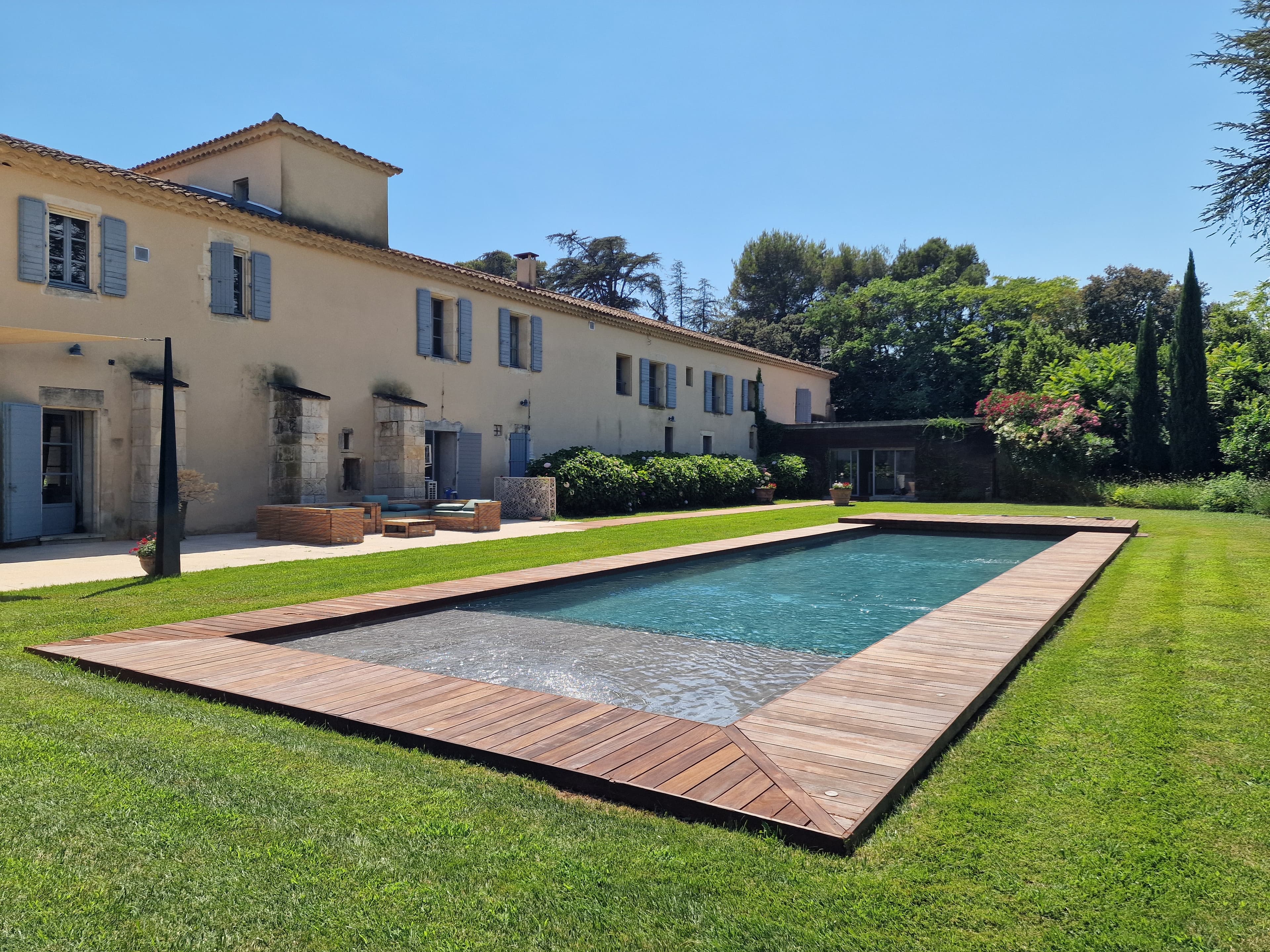 Piscine du domaine bordée d'une terrasse en bois, face au parc